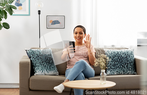 Image of woman with smartphone having video call at home