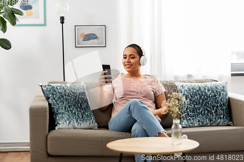 Image of woman with smartphone listening to music at home