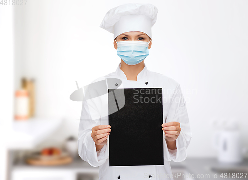 Image of female chef in face mask with black menu tablet