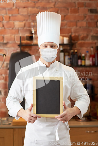 Image of male chef in face mask with black menu chalk board