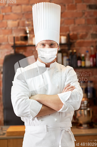 Image of male chef in face mask at restaurant kitchen