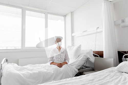 Image of old woman patient in mask lying in bed at hospital