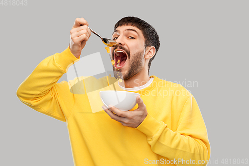 Image of hungry young man eating cereals