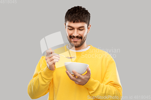 Image of happy smiling young man eating cereals