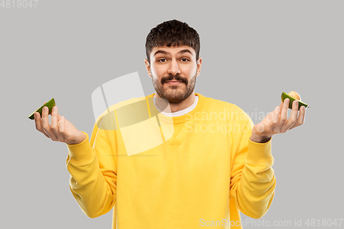 Image of confused young man with avocado shrugging