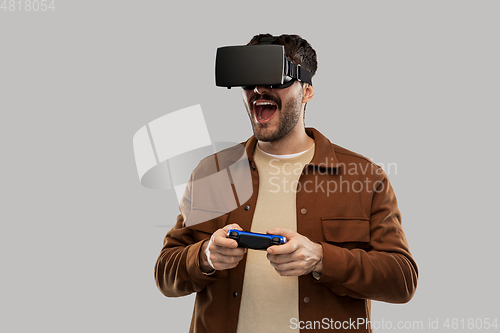Image of happy smiling young man in vr glasses with gamepad