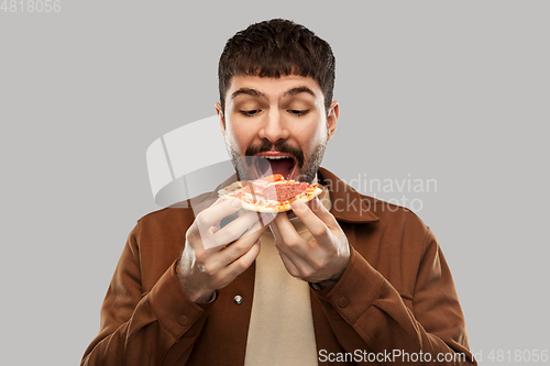 Image of hungry young man eating pizza