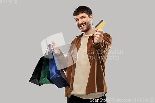 Image of happy young man with shopping bags and credit card