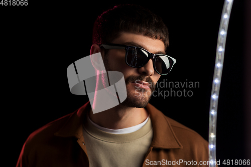 Image of man in sunglasses over neon lights at nightclub