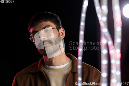 Image of man in glasses over neon lights at nightclub