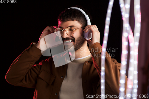 Image of man in headphones over neon lights of night club