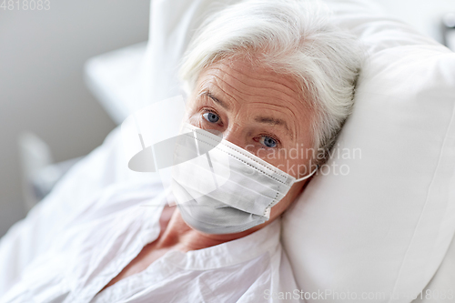 Image of old woman patient in mask lying in bed at hospital