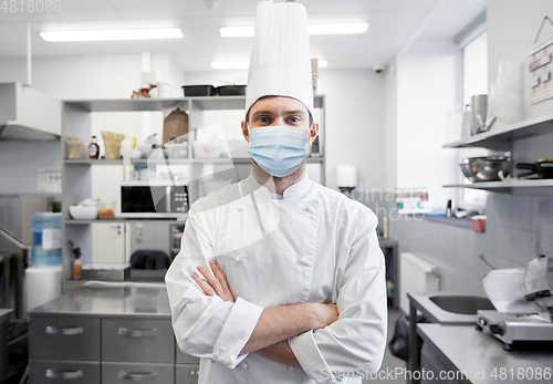 Image of male chef with in face mask at restaurant kitchen