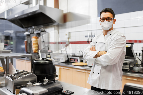 Image of male chef with in face mask at kebab shop kitchen