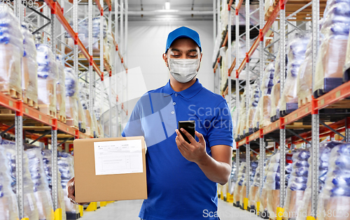 Image of delivery man in mask with cellphone and parcel box