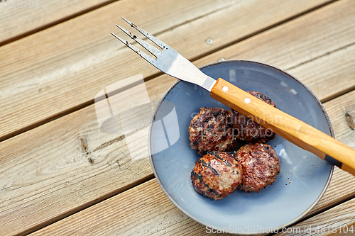 Image of roasted meat cutlets on plate with barbeque fork