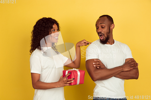 Image of Valentine\'s day celebration, happy african-american couple isolated on yellow background