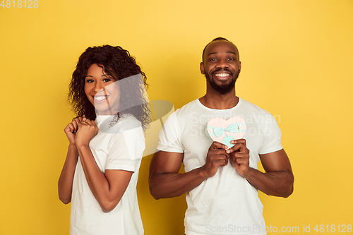 Image of Valentine\'s day celebration, happy african-american couple isolated on yellow background