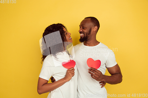 Image of Valentine\'s day celebration, happy african-american couple isolated on yellow background