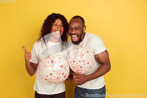 Image of Valentine\'s day celebration, happy african-american couple isolated on yellow background