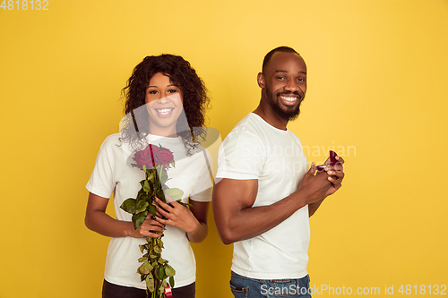 Image of Valentine\'s day celebration, happy african-american couple isolated on yellow background