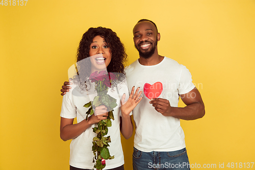 Image of Valentine\'s day celebration, happy african-american couple isolated on yellow background