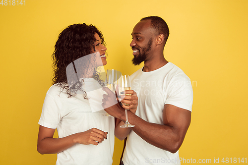 Image of Valentine\'s day celebration, happy african-american couple isolated on yellow background