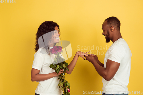 Image of Valentine\'s day celebration, happy african-american couple isolated on yellow background