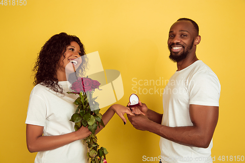 Image of Valentine\'s day celebration, happy african-american couple isolated on yellow background