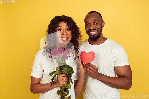 Image of Valentine\'s day celebration, happy african-american couple isolated on yellow background