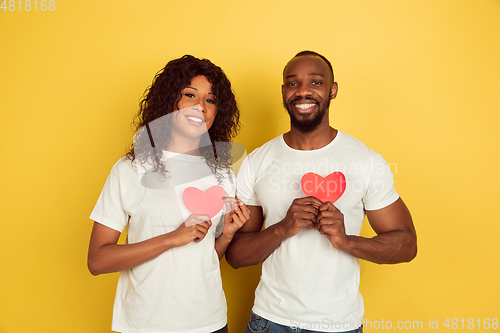 Image of Valentine\'s day celebration, happy african-american couple isolated on yellow background
