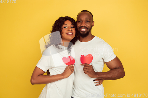 Image of Valentine\'s day celebration, happy african-american couple isolated on yellow background