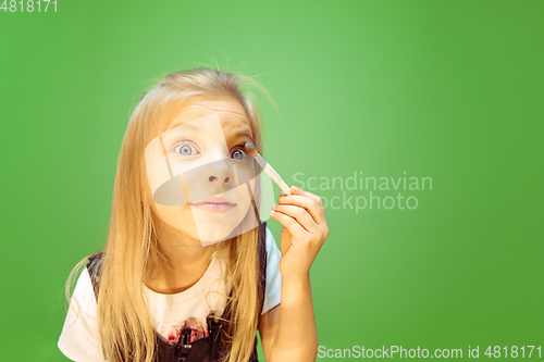 Image of Little girl dreaming about future profession of makeup artist