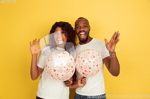 Image of Valentine\'s day celebration, happy african-american couple isolated on yellow background