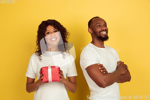 Image of Valentine\'s day celebration, happy african-american couple isolated on yellow background