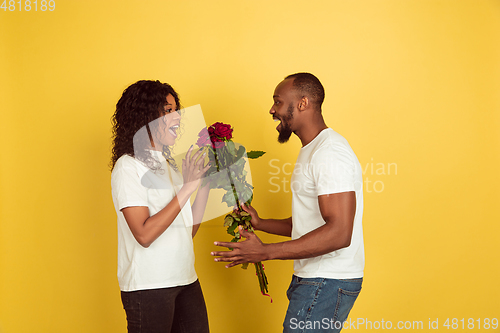 Image of Valentine\'s day celebration, happy african-american couple isolated on yellow background