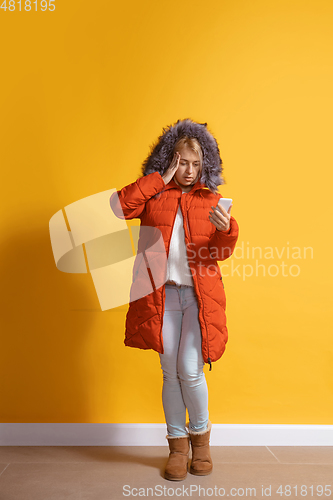 Image of Young caucasian woman using smartphone. Full body length portrait isolated over yellow background.