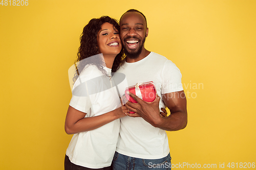 Image of Valentine\'s day celebration, happy african-american couple isolated on yellow background