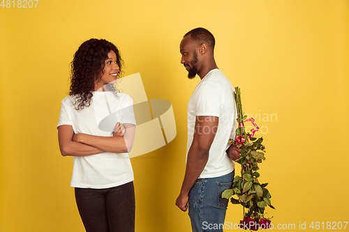 Image of Valentine\'s day celebration, happy african-american couple isolated on yellow background