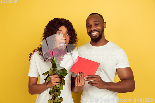 Image of Valentine\'s day celebration, happy african-american couple isolated on yellow background