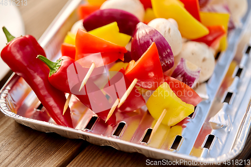 Image of close up of vegetables on skewers on foil grill