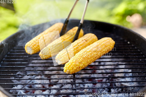 Image of close up of corn roasting on grill outdoors