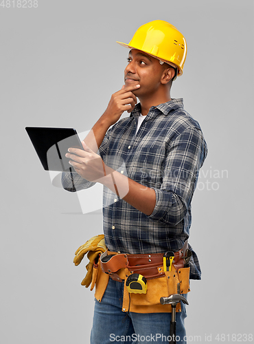 Image of thinking indian builder in helmet with tablet pc