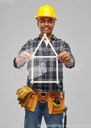 Image of happy indian builder with ruler in shape of home