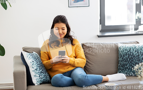 Image of happy asian young woman with smartphone at home