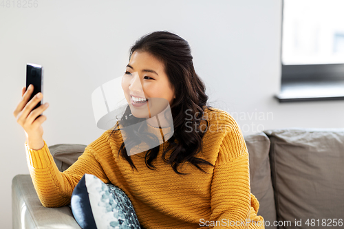 Image of asian woman taking selfie with smartphone at home