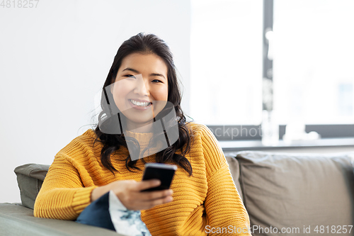 Image of happy asian young woman with smartphone at home