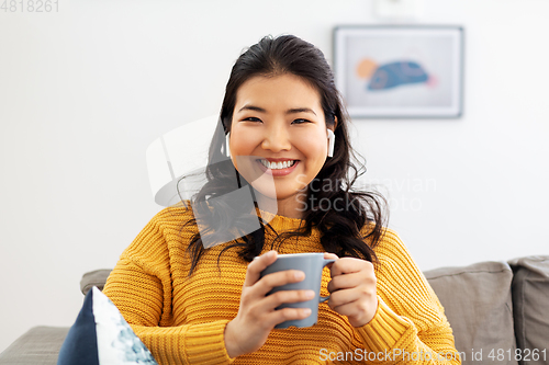 Image of woman in earphones listening to music at home