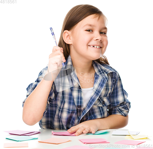 Image of Girl is writing on color stickers using pen