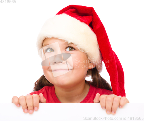 Image of Little girl in santa hat is holding blank board